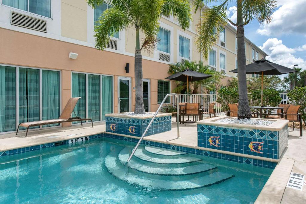 a swimming pool with palm trees and a building at Sleep Inn & Suites Port Charlotte-Punta Gorda in Port Charlotte