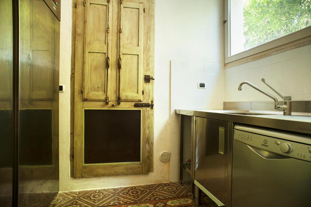 - une cuisine avec un évier et une porte en bois dans l'établissement Wp RELAIS LOCANDA FIORE DI ZAGARA, à Diso