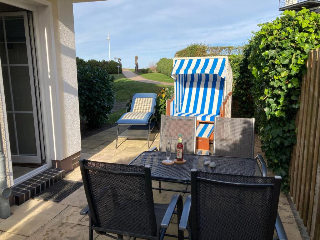 a patio with chairs and a table with a bottle of beer at Strandtraum in Glowe