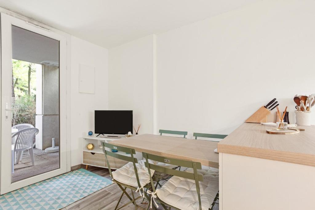 eine Küche mit einem Tisch und Stühlen sowie einem TV in der Unterkunft Appartement Le Lavandou - Cavalière in Le Lavandou
