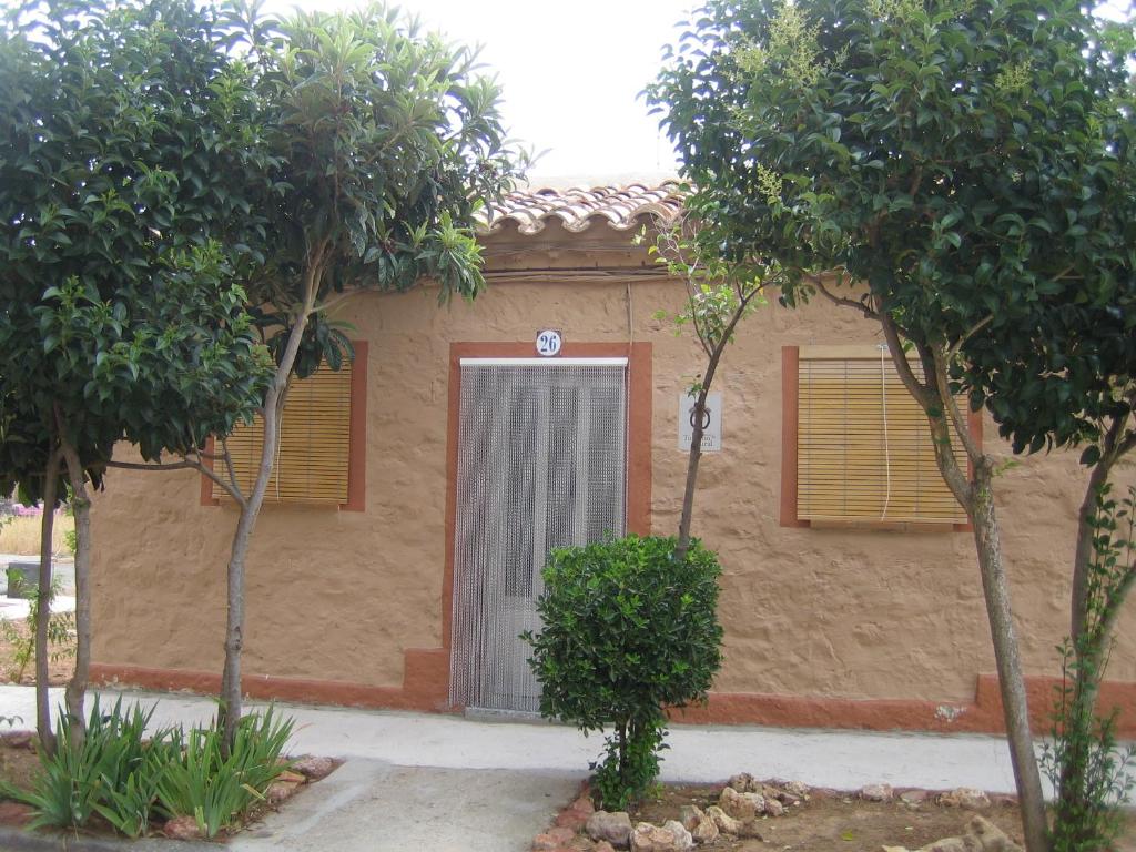 un bâtiment avec une porte et des arbres devant lui dans l'établissement Casa Rural Los Pinos, à Valmuel