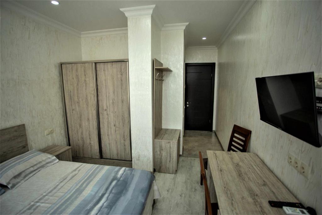 Un dormitorio con una cama, una mesa y un televisor. en A cozy apartments, en Batumi