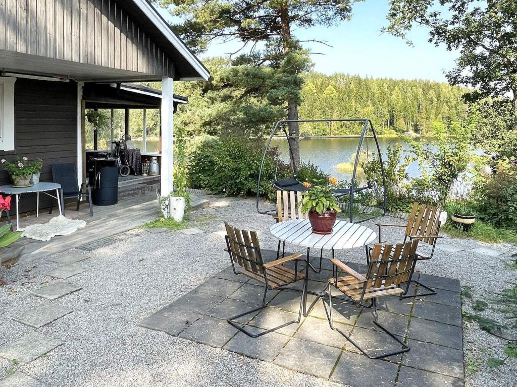 a patio with a table and chairs next to a lake at 4 star holiday home in LJUSFALLSHAMMAR in Kolvetorp