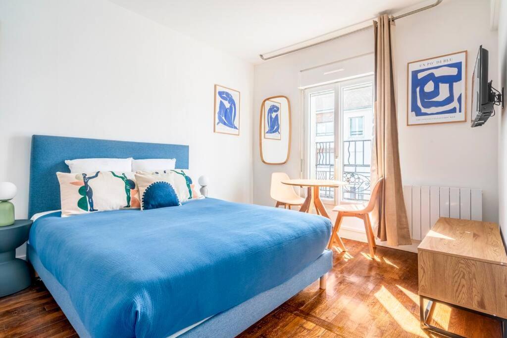 - une chambre avec un lit bleu et une table dans l'établissement Studio ensoleillé aux portes de Paris Montreuil-II, à Montreuil