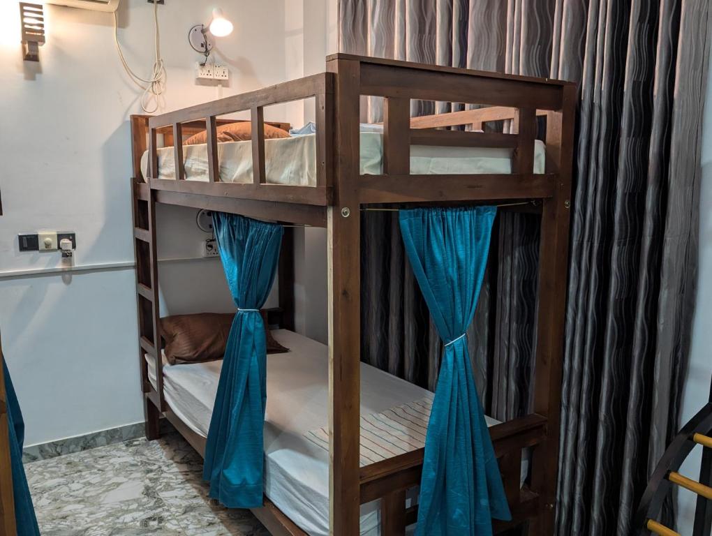 two bunk beds in a room with blue curtains at Costels Mirissa in Mirissa