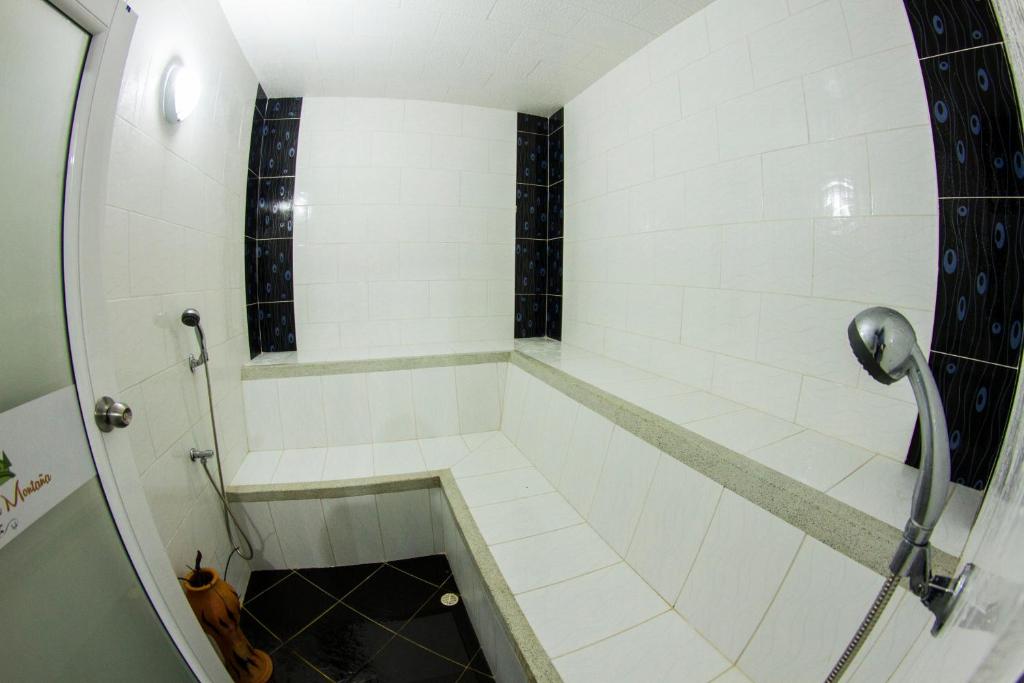 a bathroom with a shower with white tiles at Hotel La Montaña San Gil in San Gil