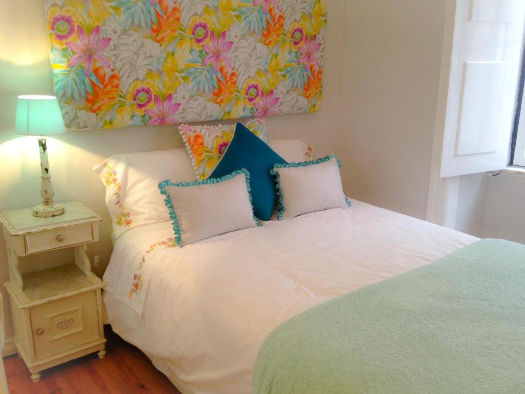リスボンにあるShabby Chic Flat 2の白いベッドと壁に絵画が飾られたベッドルーム1室
