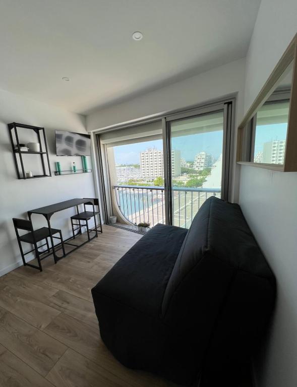 une chambre avec un lit et un balcon avec une table et des chaises dans l'établissement Studio rénové en plein centre ville, sur le port, vue mer, à La Grande Motte