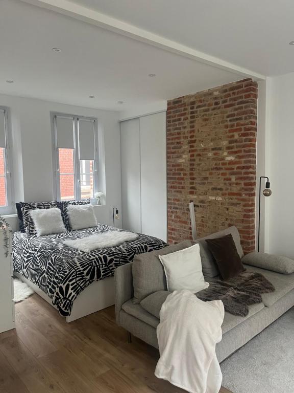 une chambre avec un lit et un canapé et un mur de briques dans l'établissement DAUTRESIRE, au Tréport