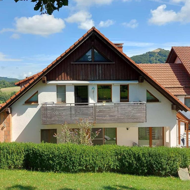 a house with a wooden roof with a balcony at Ferienwohnungen Lahmenhof in Poppenhausen
