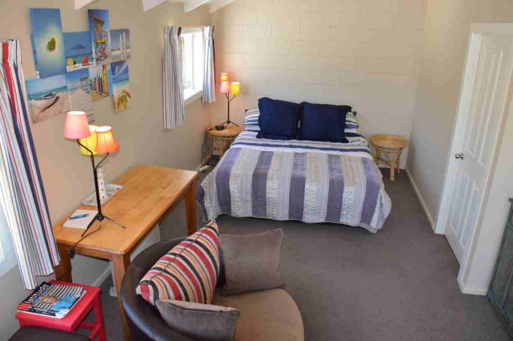 a bedroom with a bed and a desk and a chair at Le Loft in Akaroa