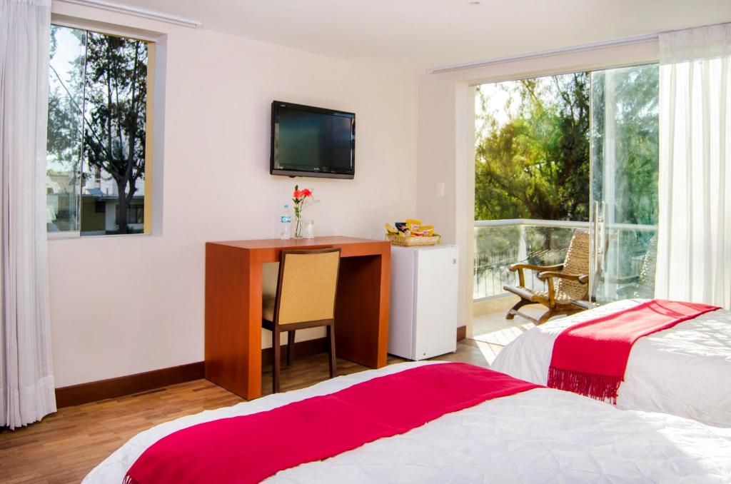 a bedroom with a desk and a television on the wall at Alwa Hotel Boutique Standard in Arequipa