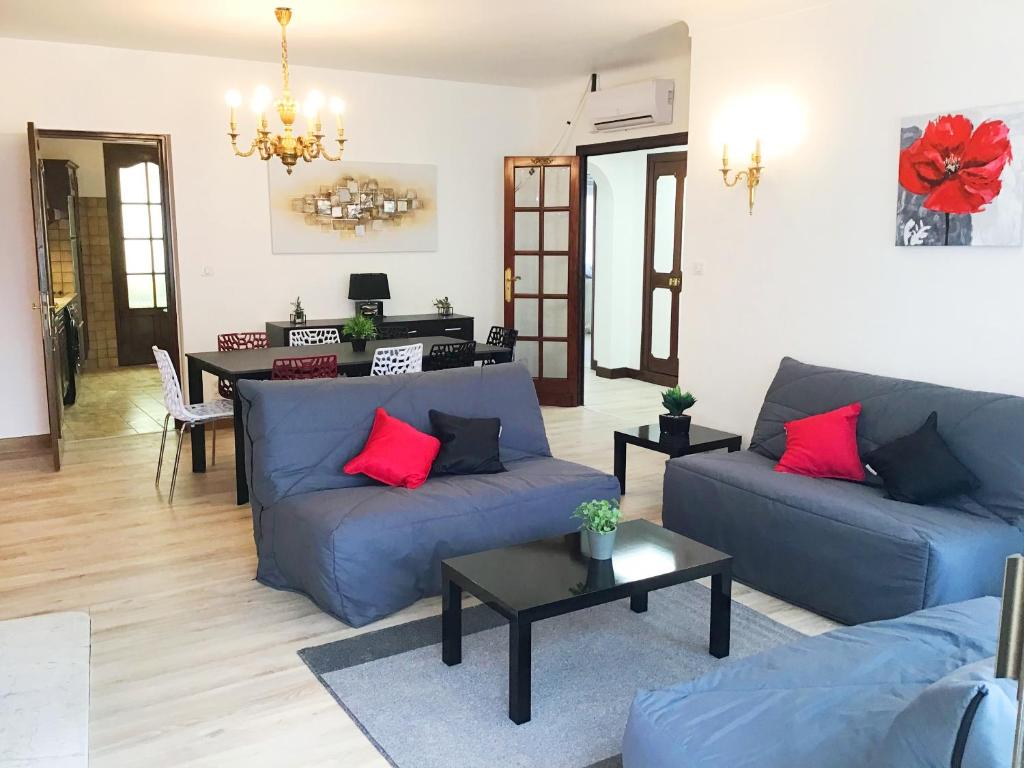 ein Wohnzimmer mit blauen Sofas und roten Kissen in der Unterkunft Appartement le Soleil 140 m2 climatisé parking privé proche Sanctuaires in Lourdes