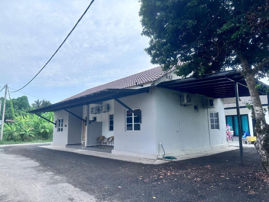 a small white house with a tree in front of it at Saliff Cottage 1 in Kampong Haji Musa