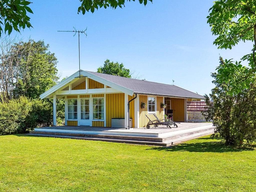 a yellow house with a porch and a yard at 4 person holiday home in LÖTTORP in Löttorp