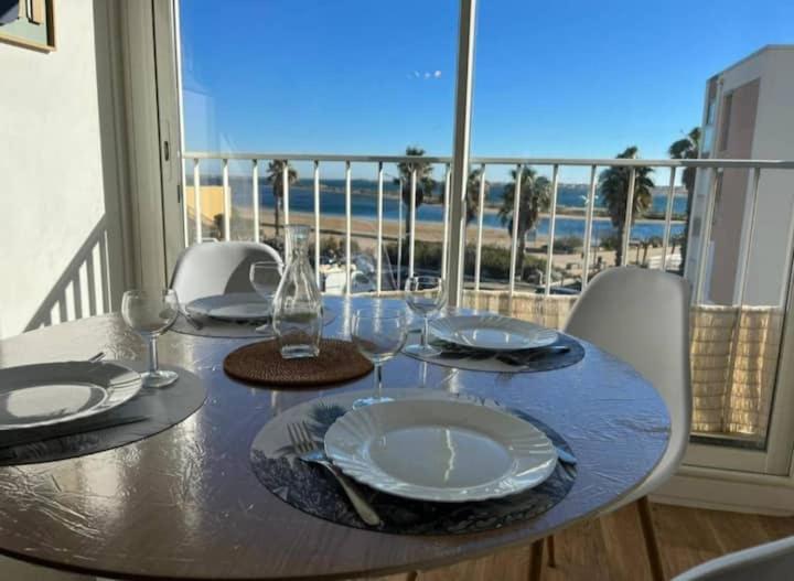 une table avec des assiettes et des verres à vin sur un balcon dans l'établissement Appartement vue mer, plage à 20m, à Gruissan