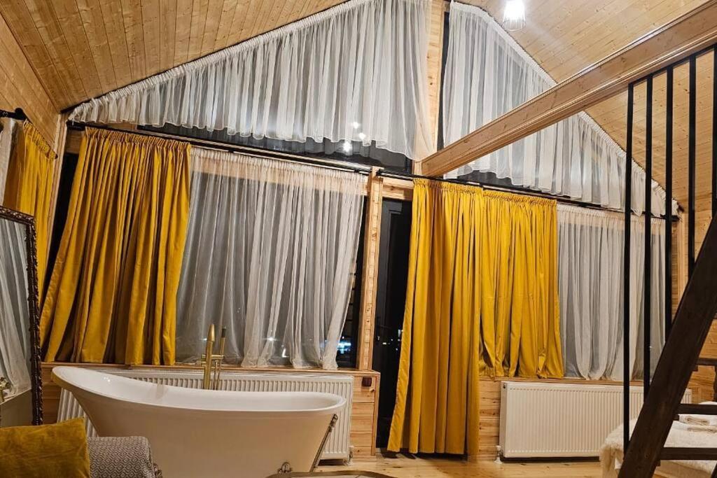a bathroom with yellow curtains and a bath tub at mood villa kazbegi in Kazbegi