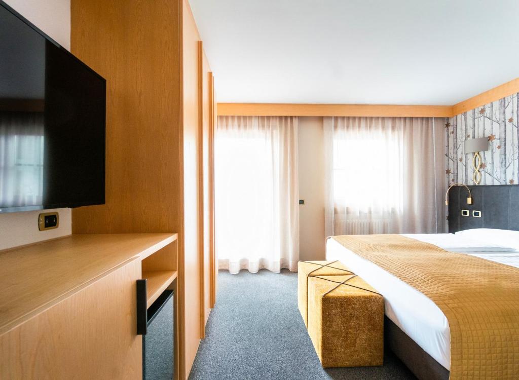 a hotel room with a bed and a flat screen tv at Garni Aritz in Campitello di Fassa