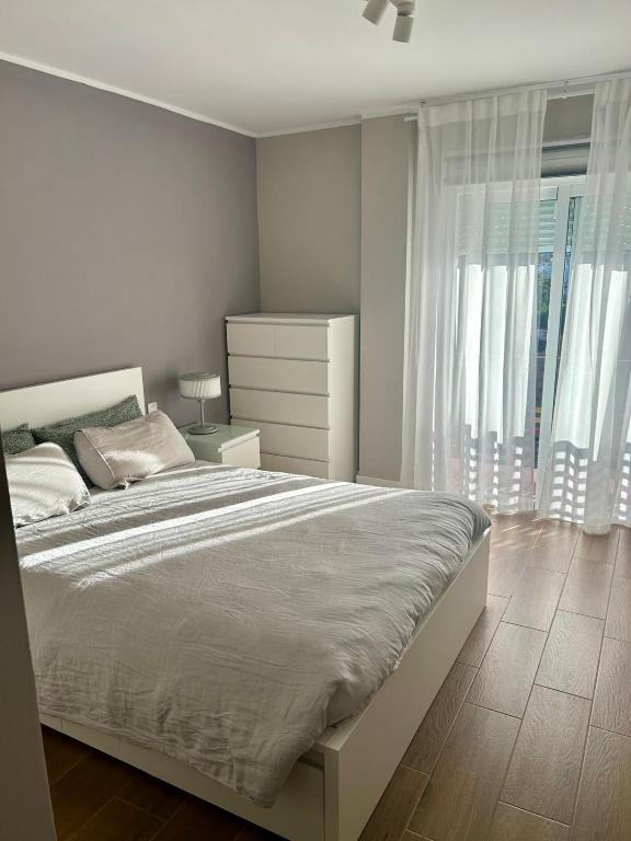a white bedroom with a large bed and a window at Calm House in Arona