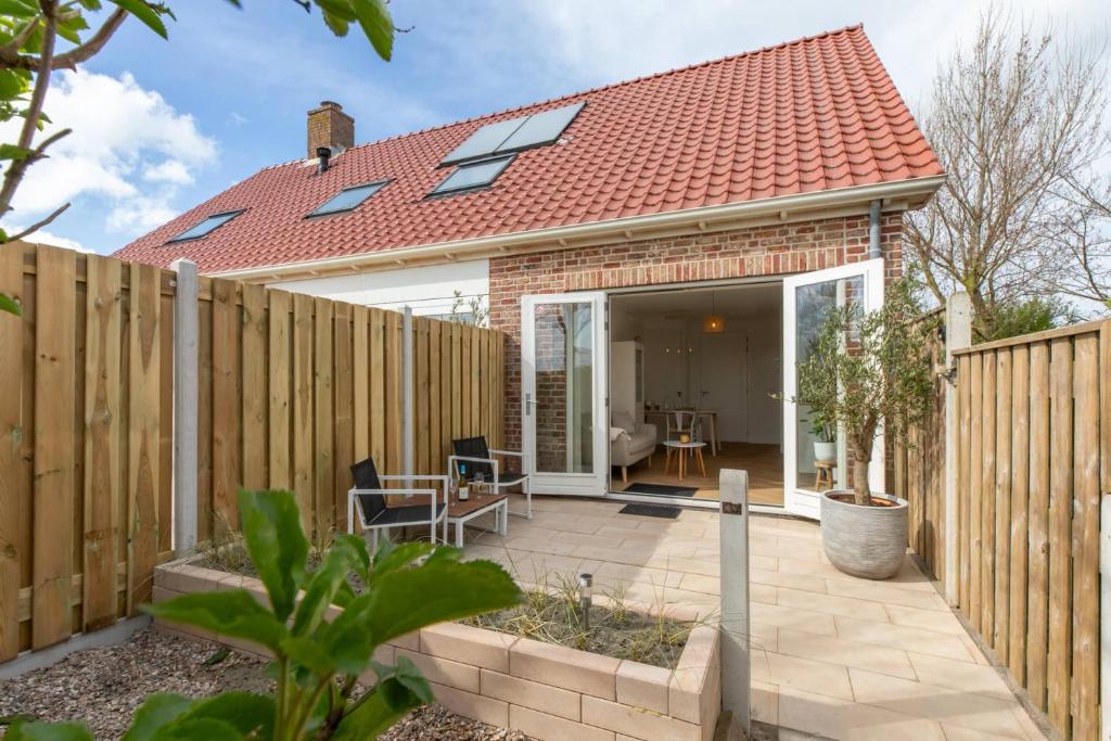 a home with a wooden fence and a patio at Hello Zeeland - Appartement Kusthuys 2 - 2025 in Zoutelande
