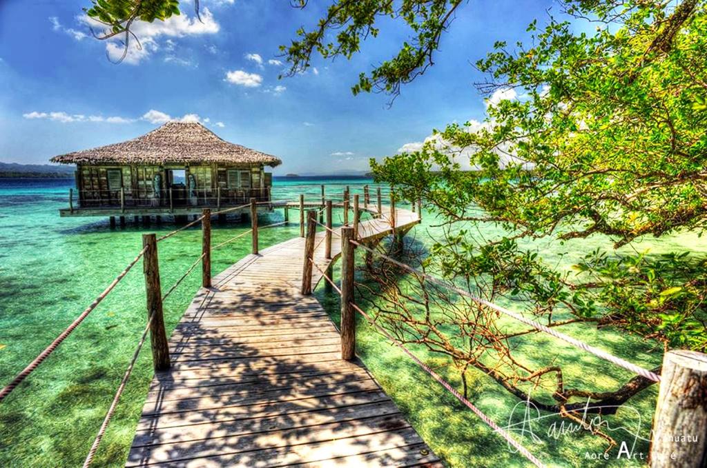 ein Pier, der zu einer Hütte im Wasser führt in der Unterkunft Ratua Private Island Resort in Aimbuei Bay