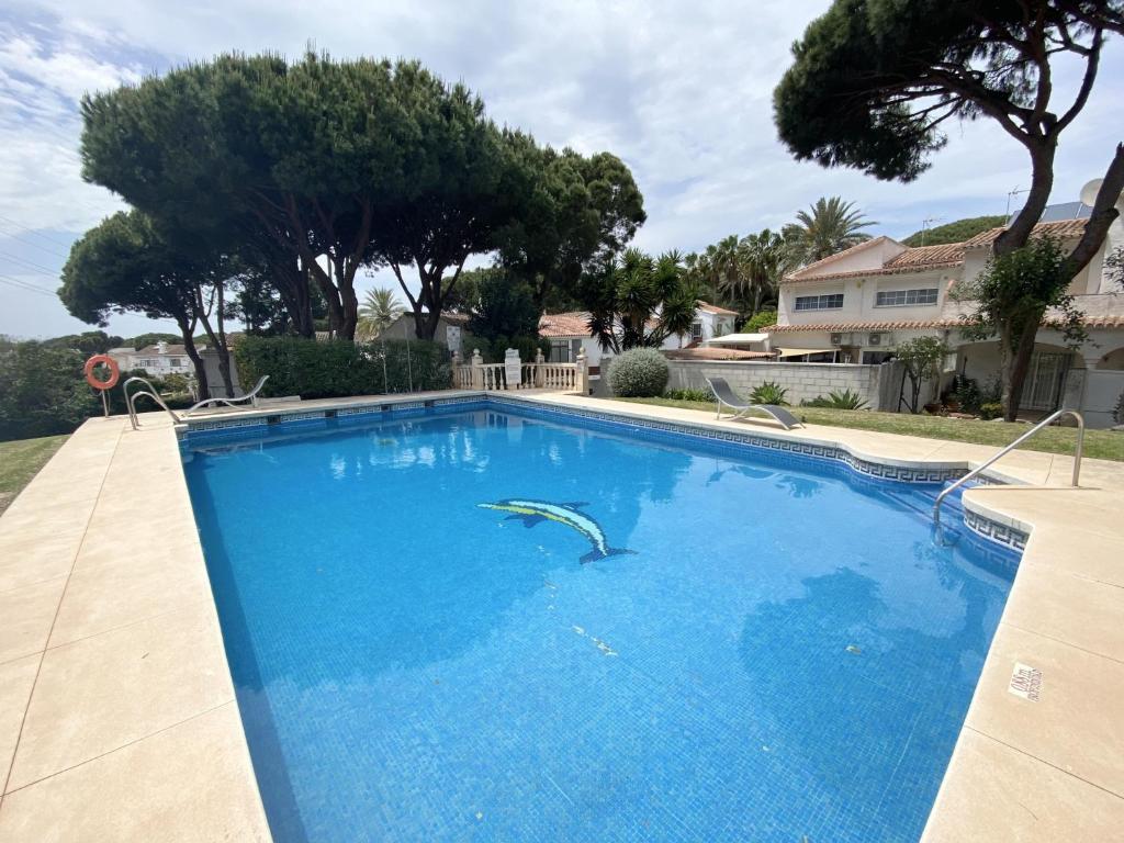 a large blue swimming pool in a yard with trees at N02 Los Rosales - Studio in Sitio de Calahonda