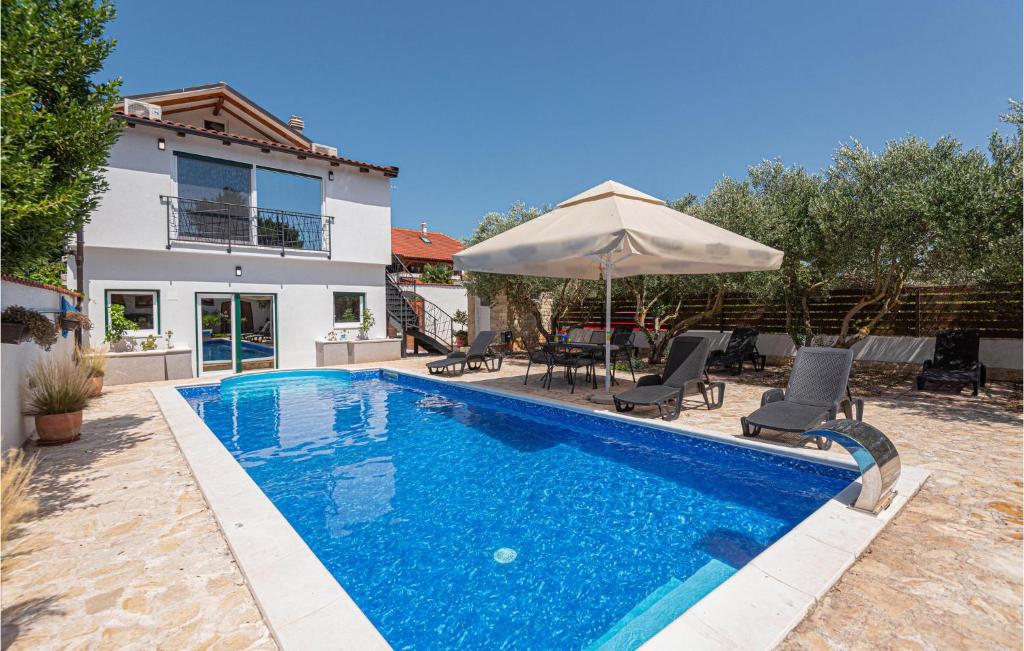 una piscina frente a una casa con sombrilla en Nice Apartment In Dubrava Kod Sibenika, en Dubrava
