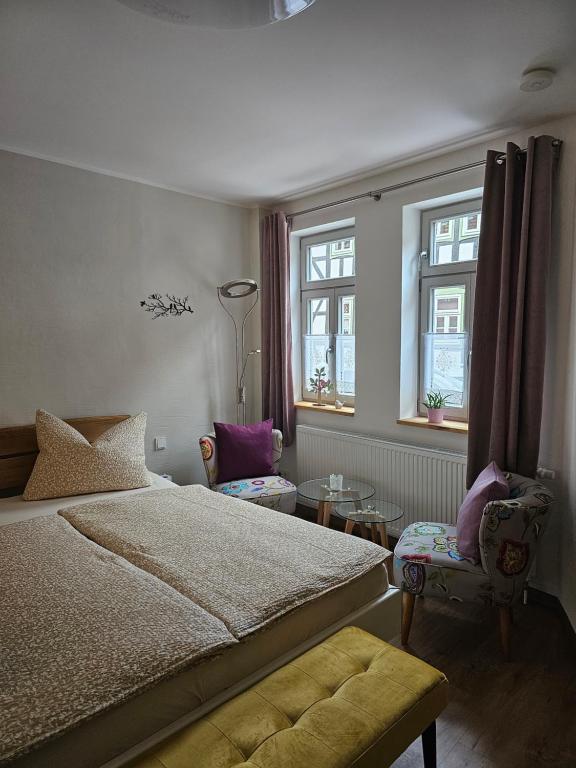 a bedroom with a bed and a table and windows at Ferienhaus Fachwerk 97 in Stolberg i. Harz