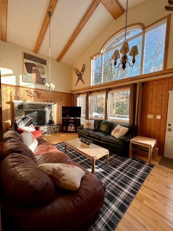 a living room with a leather couch and a fireplace at Cozy Chalet at Jay Peak in Montgomery Center