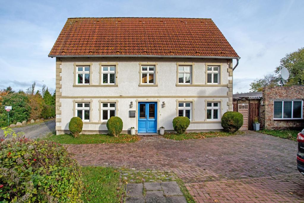 una gran casa blanca con una puerta azul en Bäckerhus - Ferienwohnung 2, en Wiek auf Rügen