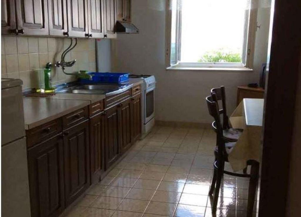 a kitchen with a sink and a stove and a window at Apartments Sova in Postira