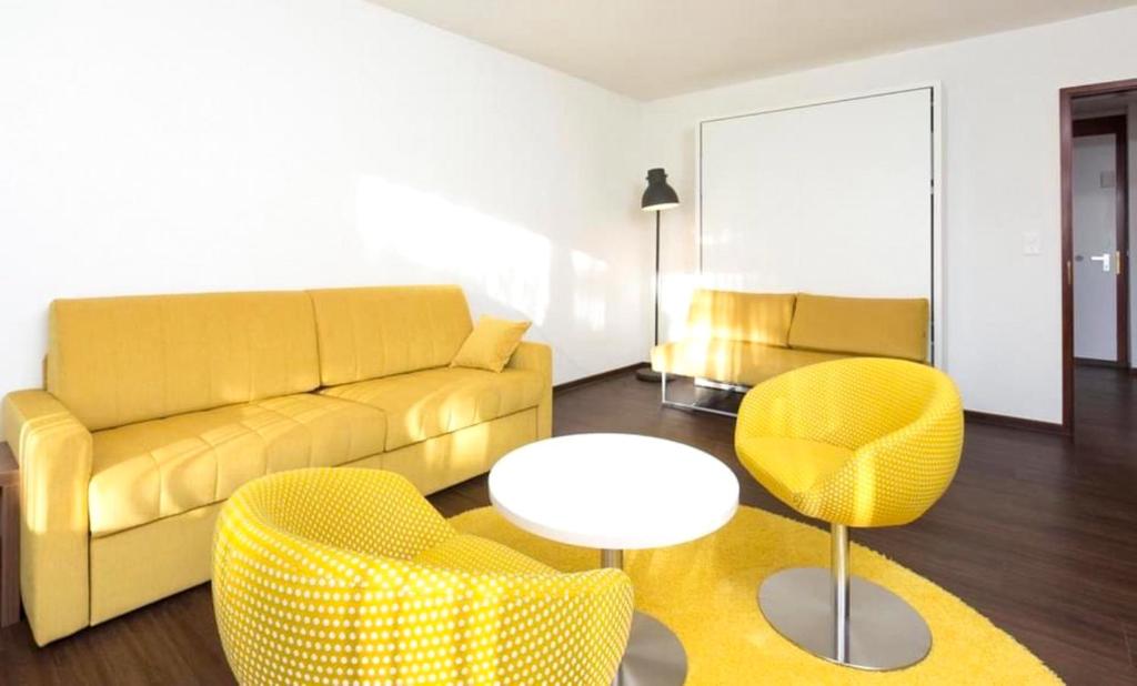 a living room with a yellow couch and chairs at Residence Caddies Club in Crans-Montana