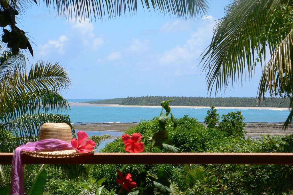 - un chapeau et des fleurs assis sur un balcon donnant sur l'océan dans l'établissement Alizées Moreré, à Île de Boipeba