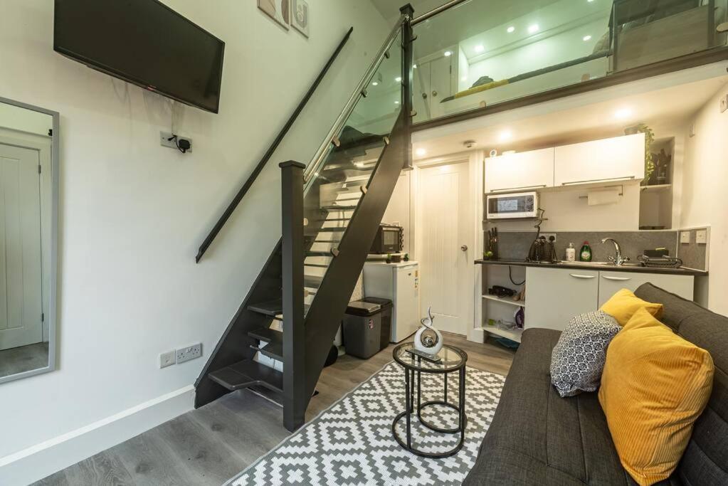 a living room with a couch and a staircase at Quirky Studio in Central Reading in Reading