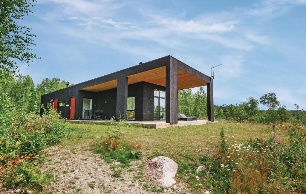a black house on top of a grass field at Three-Bedroom Holiday Home Holmsjö With A Fireplace 06 in Holmsjö