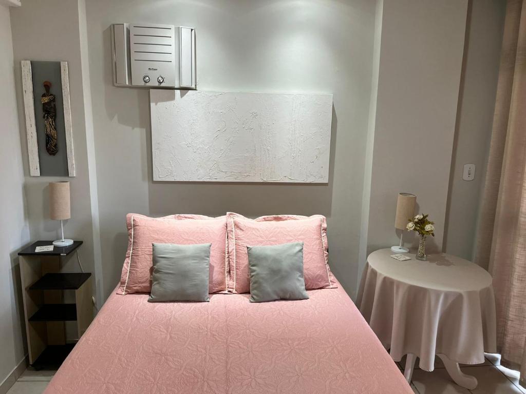 a pink bed with two pillows and a table at O PARAÍSO É AQUI! Apto muito próximo a praia in Guarapari