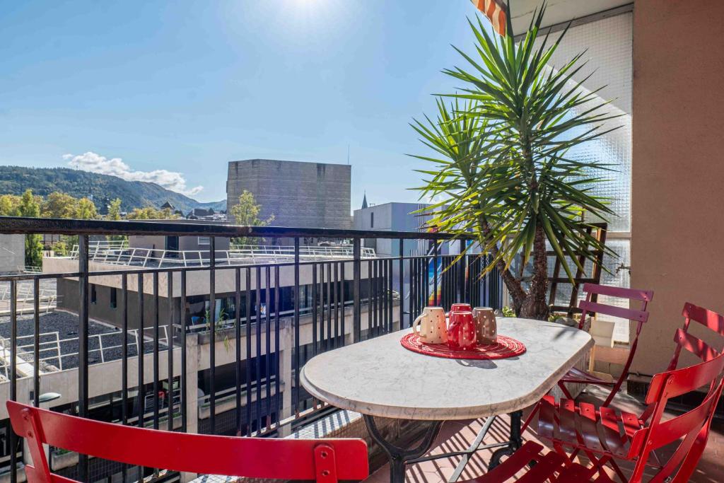 une table et des chaises sur un balcon avec vue sur une ville dans l'établissement Le Sommeiller, à Annecy