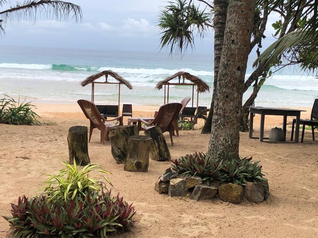 a table and chairs on a beach with the ocean at Mandy House in Habaraduwa