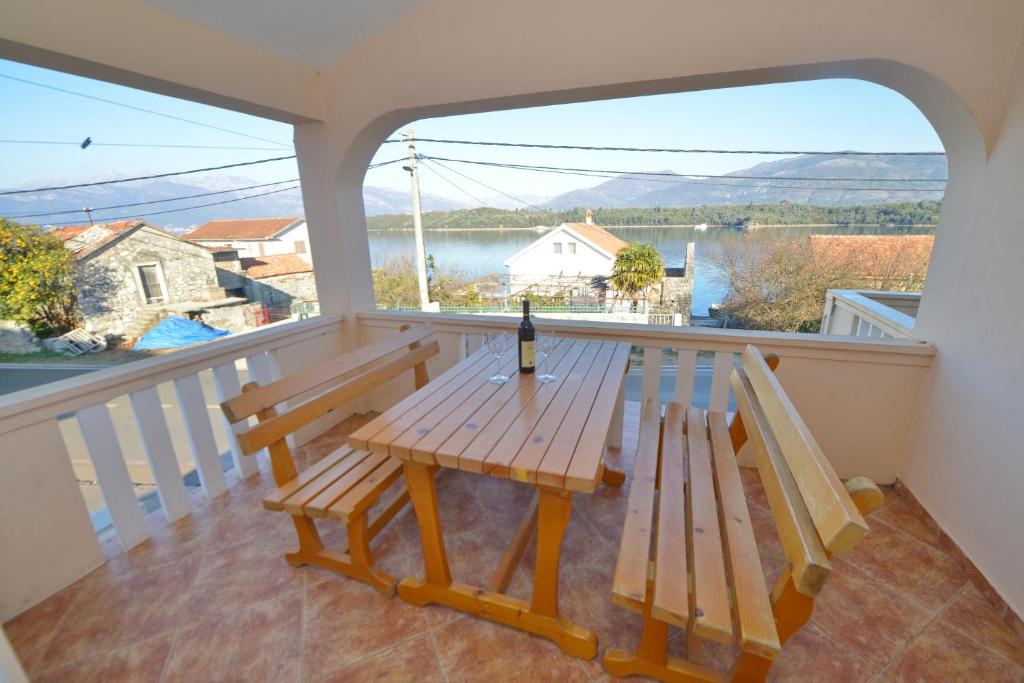 einen Picknicktisch auf einem Balkon mit einer Flasche Wein in der Unterkunft Apartments and Studios Jokić in Tivat