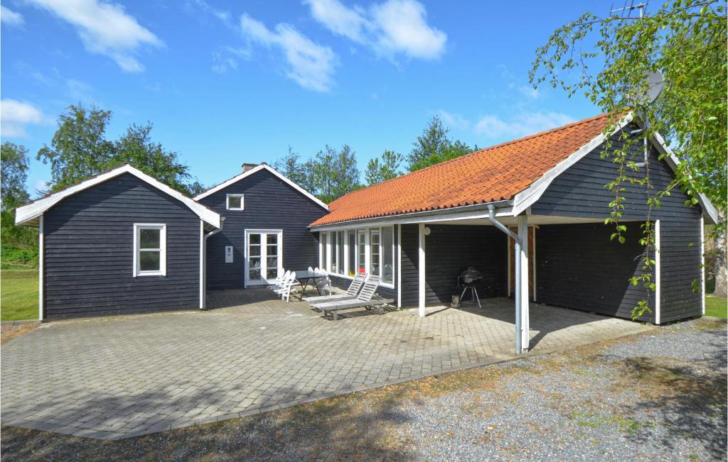 a black house with an orange roof and a patio at Cozy Home In Ebeltoft With Sauna in Ebeltoft