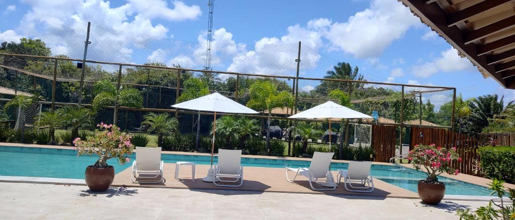 a swimming pool with lounge chairs and umbrellas next to a pool at Apartamento térreo a 300 metros da praia de Itacimirim com piscina e jardim in Itacimirim