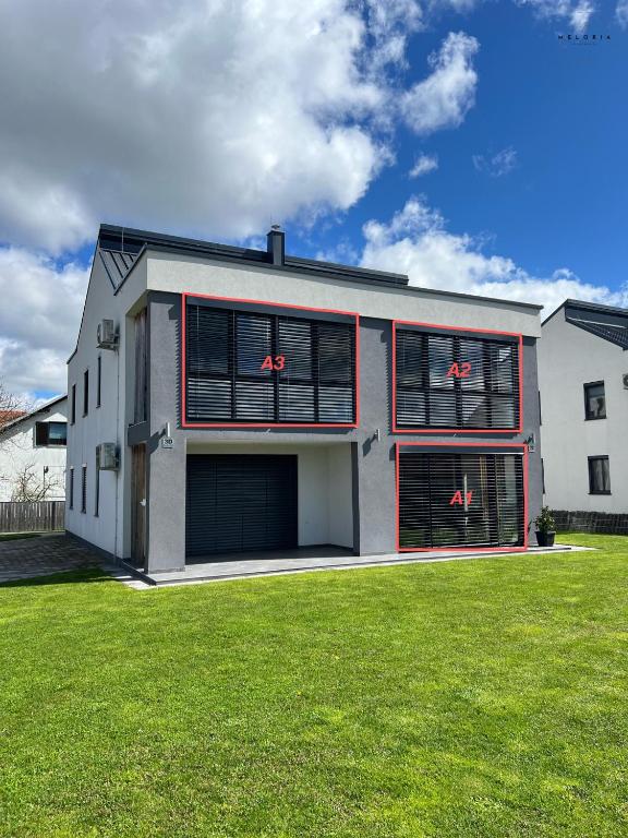 a house with two garage doors and a grass yard at Meloria Apartments in Veržej