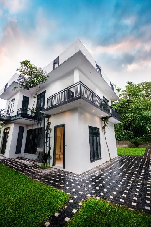a white house with a balcony and a yard at Nisansala Villa in Matara