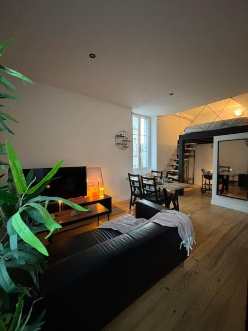 a living room with a black couch and a table at Studio industriel, mezzanine, rénové, central 201 in Saint-Étienne