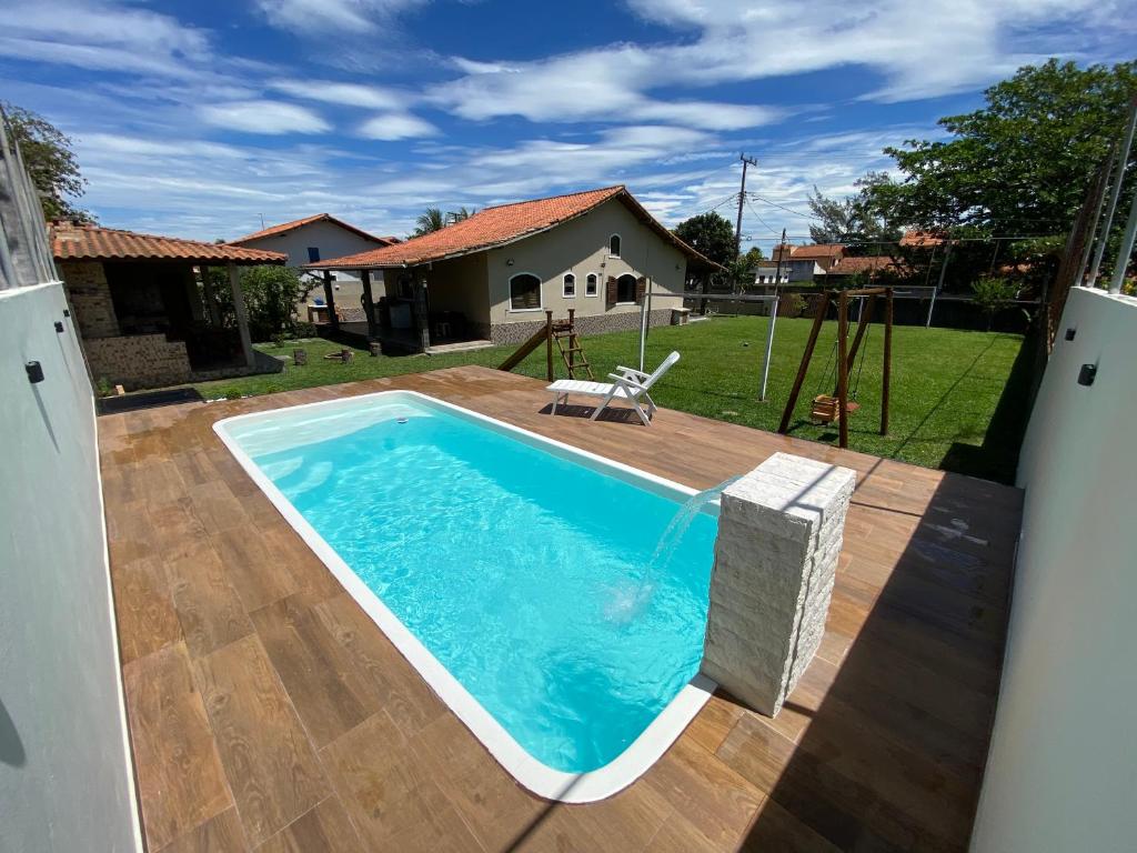a swimming pool with a wooden deck and a playground at Casa bem espaçosa com piscina, campo de futebol e área gourmet a um quarteirão da lagoa de Praia Seca in Araruama