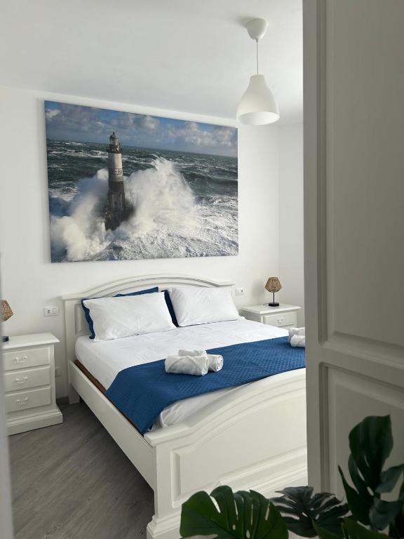 a bedroom with a bed with a lighthouse painting on the wall at SEA&SUN House in Marinella di Sarzana