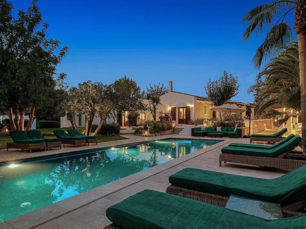 a swimming pool with chaises and chairs next to a house at Farmhouse in Ibiza with Bali Pavilion in Santa Gertrudis de Fruitera