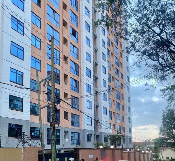 a large tall building with many windows on a street at Delight Studio, Kaisa Gardens Kileleshwa in Nairobi