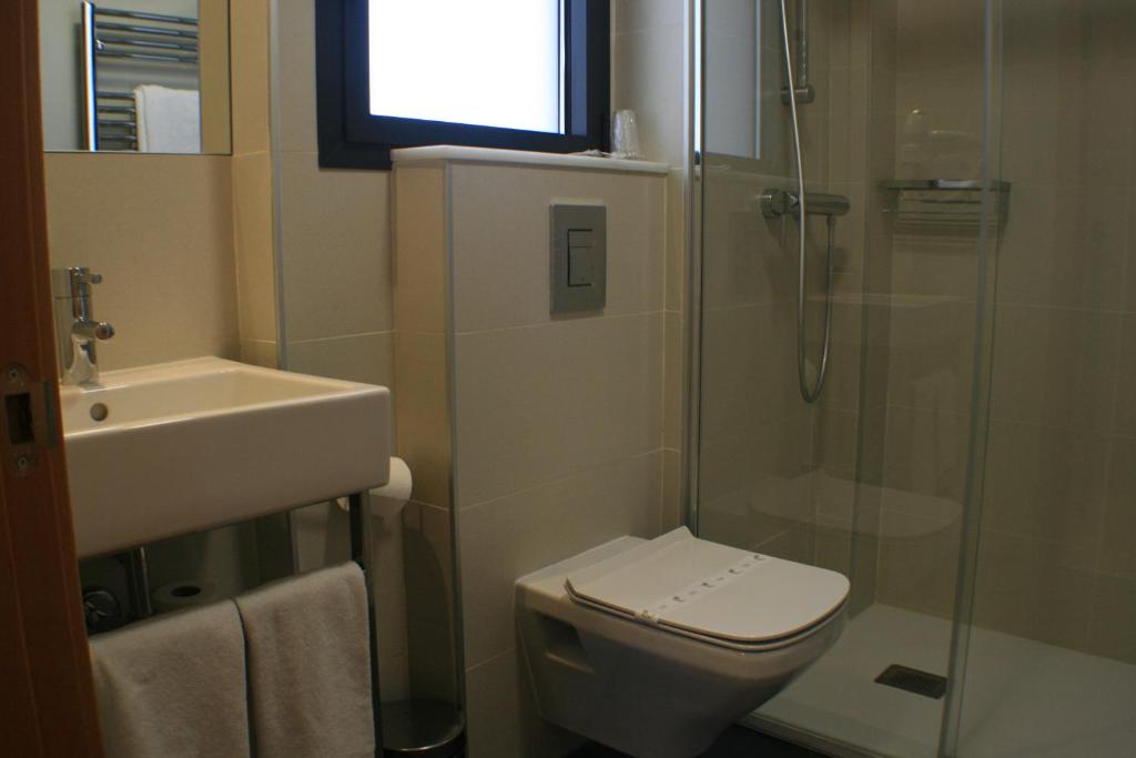 a bathroom with a toilet, sink and shower at Hotel Picos De Europa in Santander
