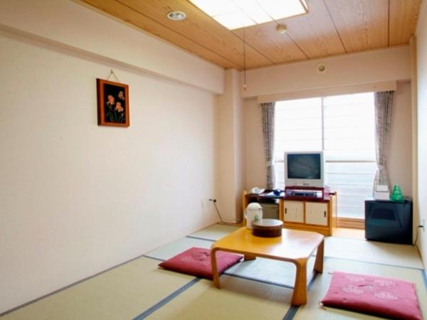 a living room with a table and a tv at Hotel Hashimoto in Sapporo
